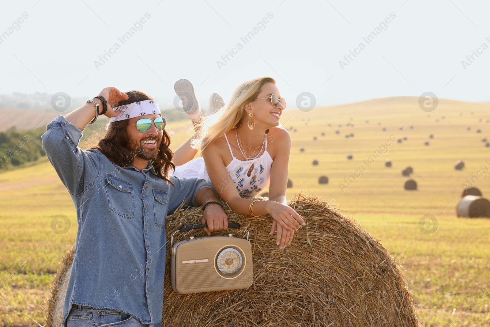 Photo of Happy hippie couple with radio receiver in field, space for text