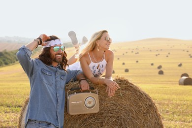 Photo of Happy hippie couple with radio receiver in field, space for text