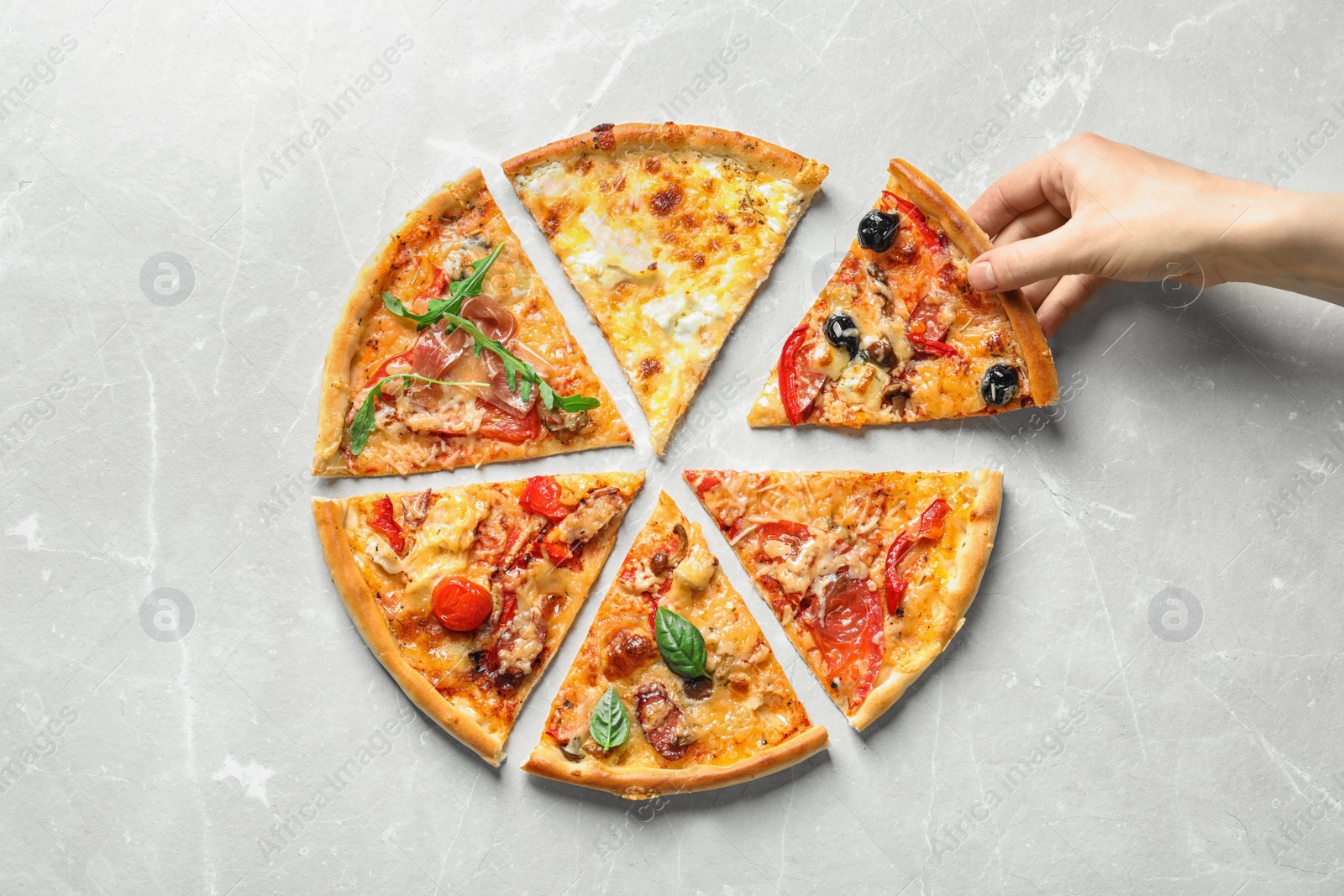 Photo of Woman taking slice of delicious pizza on light background, top view