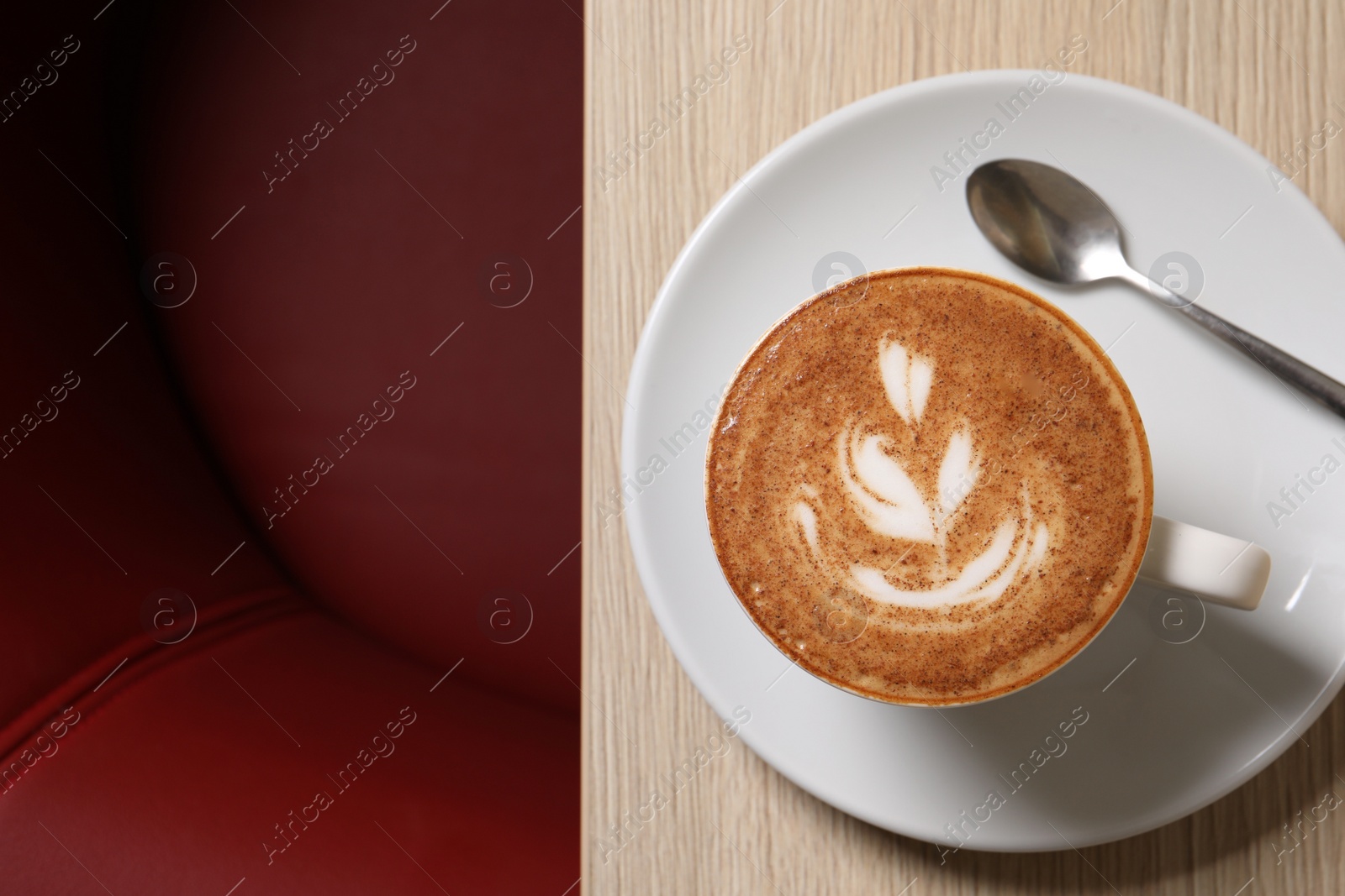 Photo of Cup of aromatic coffee and spoon on wooden table in cafe, top view. Space for text