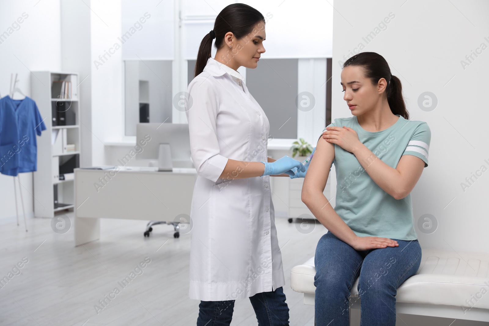 Photo of Doctor giving hepatitis vaccine to patient in clinic. Space for text