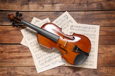 Violin and music sheets on wooden table, top view