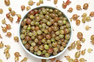 Photo of Bowl with fresh ripe gooseberries on white wooden table, flat lay