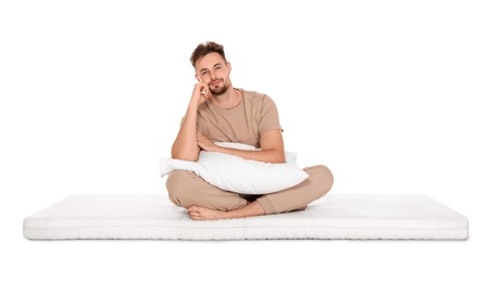Photo of Man with pillow sitting on soft mattress against white background