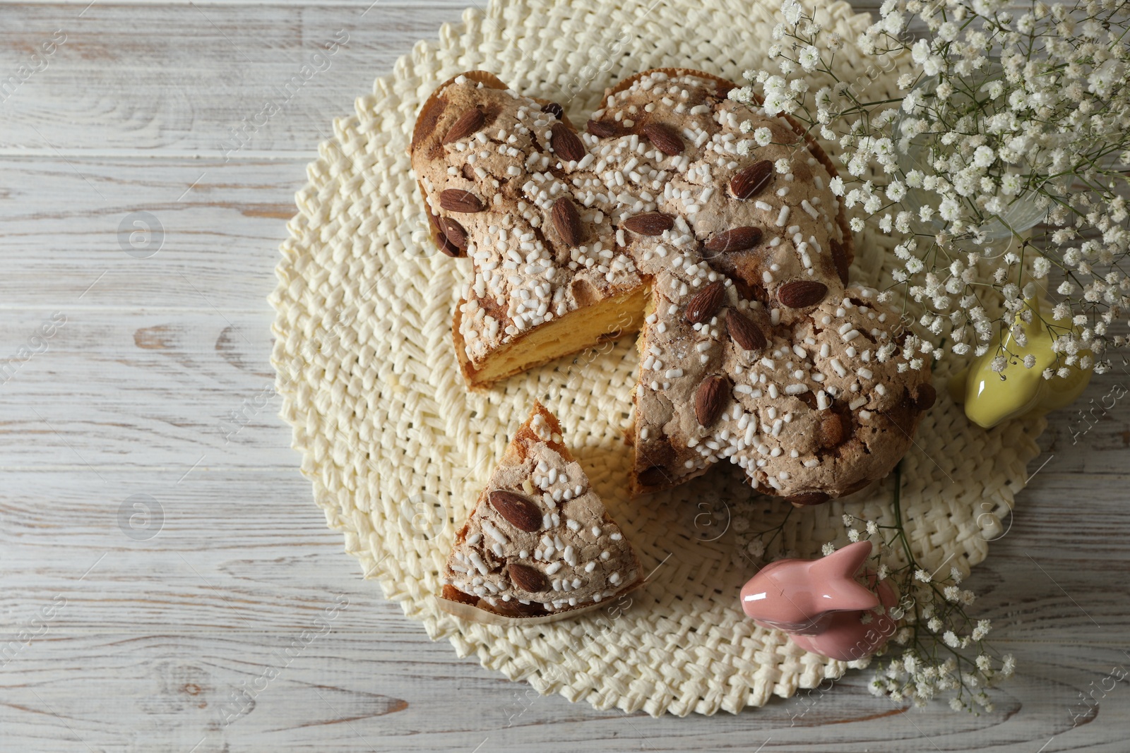 Photo of Delicious Italian Easter dove cake (traditional Colomba di Pasqua) and festive decor on white wooden table, top view. Space for text