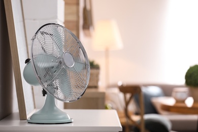 Photo of Modern electric fan on white table indoors. Space for text