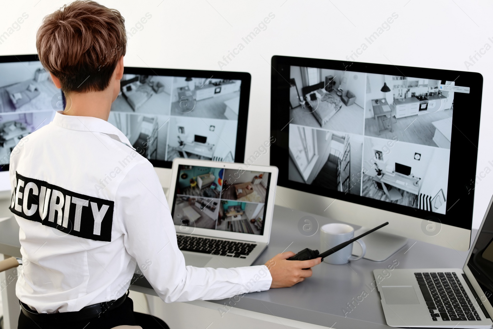 Photo of Female security guard with portable transmitter monitoring home cameras indoors