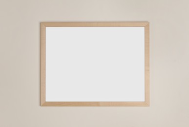 Photo of Blank frame hanging on light wall. Space for design