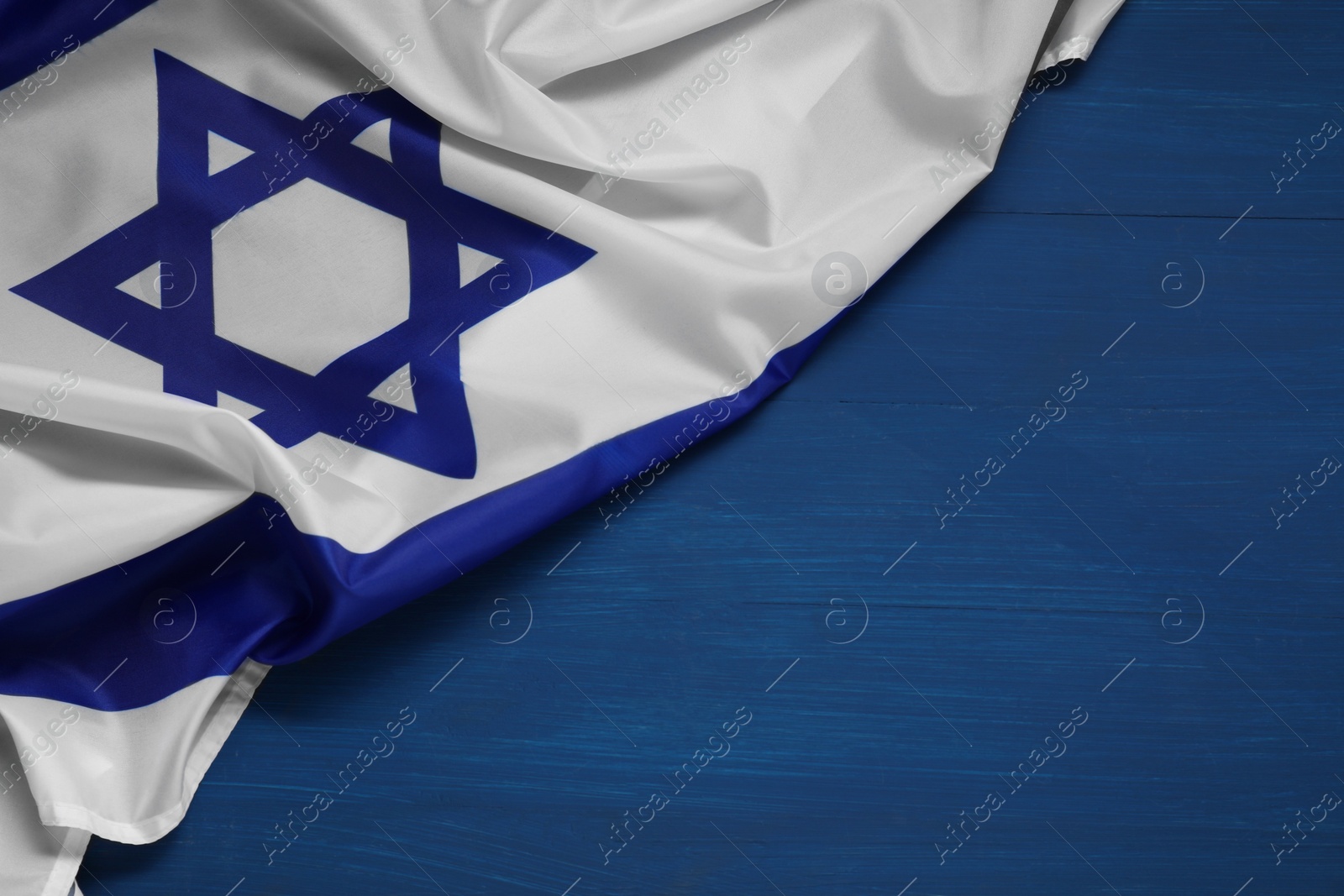 Photo of Flag of Israel on blue wooden background, above view and space for text. National symbol