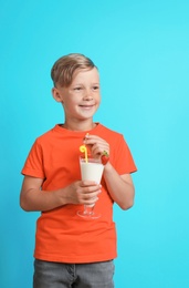 Photo of Little boy with glass of milk shake on color background