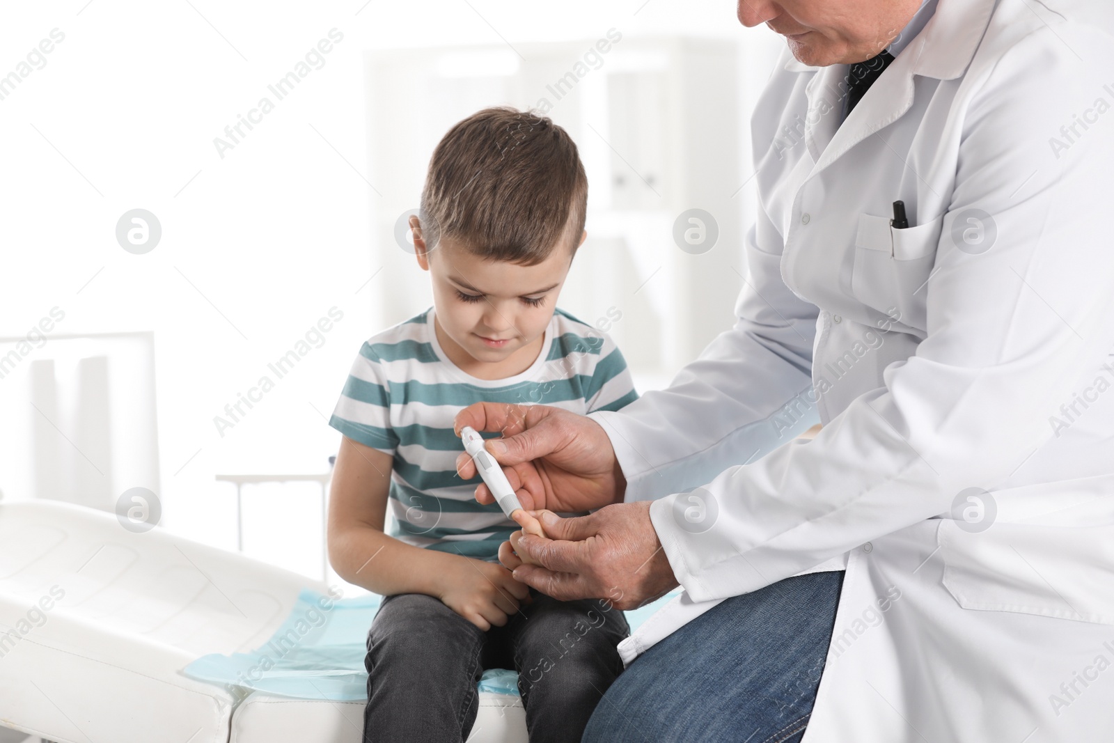 Photo of Little patient and doctor with lancet pen in hospital. Diabetes control