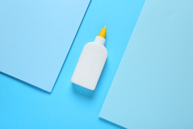 Photo of Bottleglue and paper on light blue background, flat lay