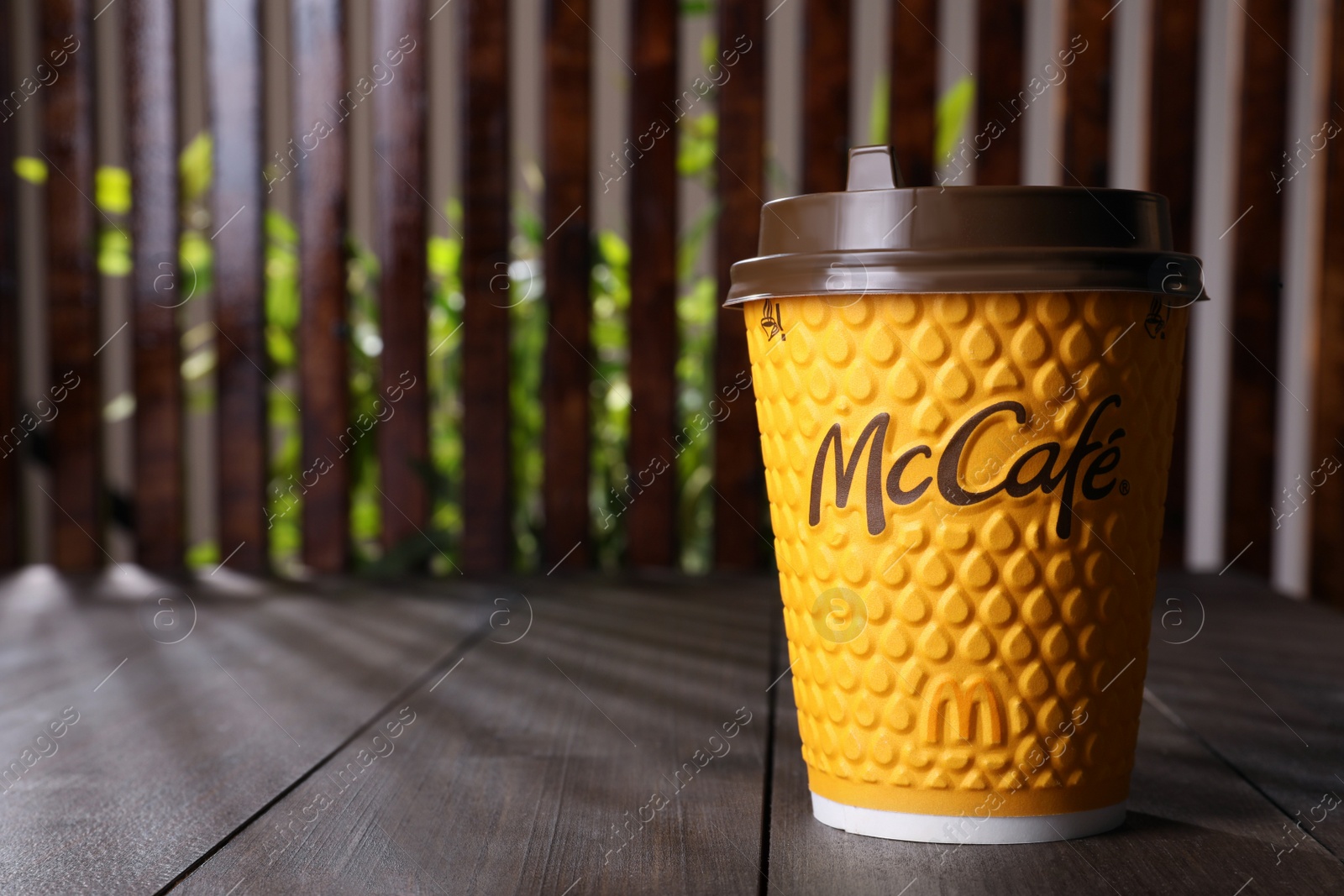 Photo of MYKOLAIV, UKRAINE - AUGUST 12, 2021: Hot McDonald's drink on wooden table. Space for text