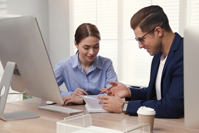 Businessman helping intern with work in office