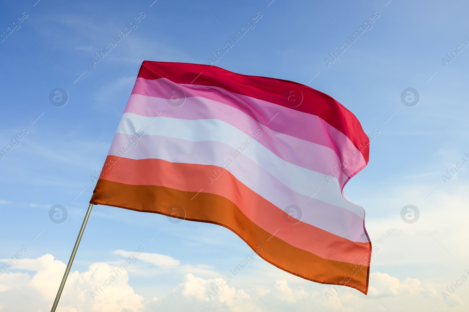 Photo of Bright lesbian flag fluttering against blue sky