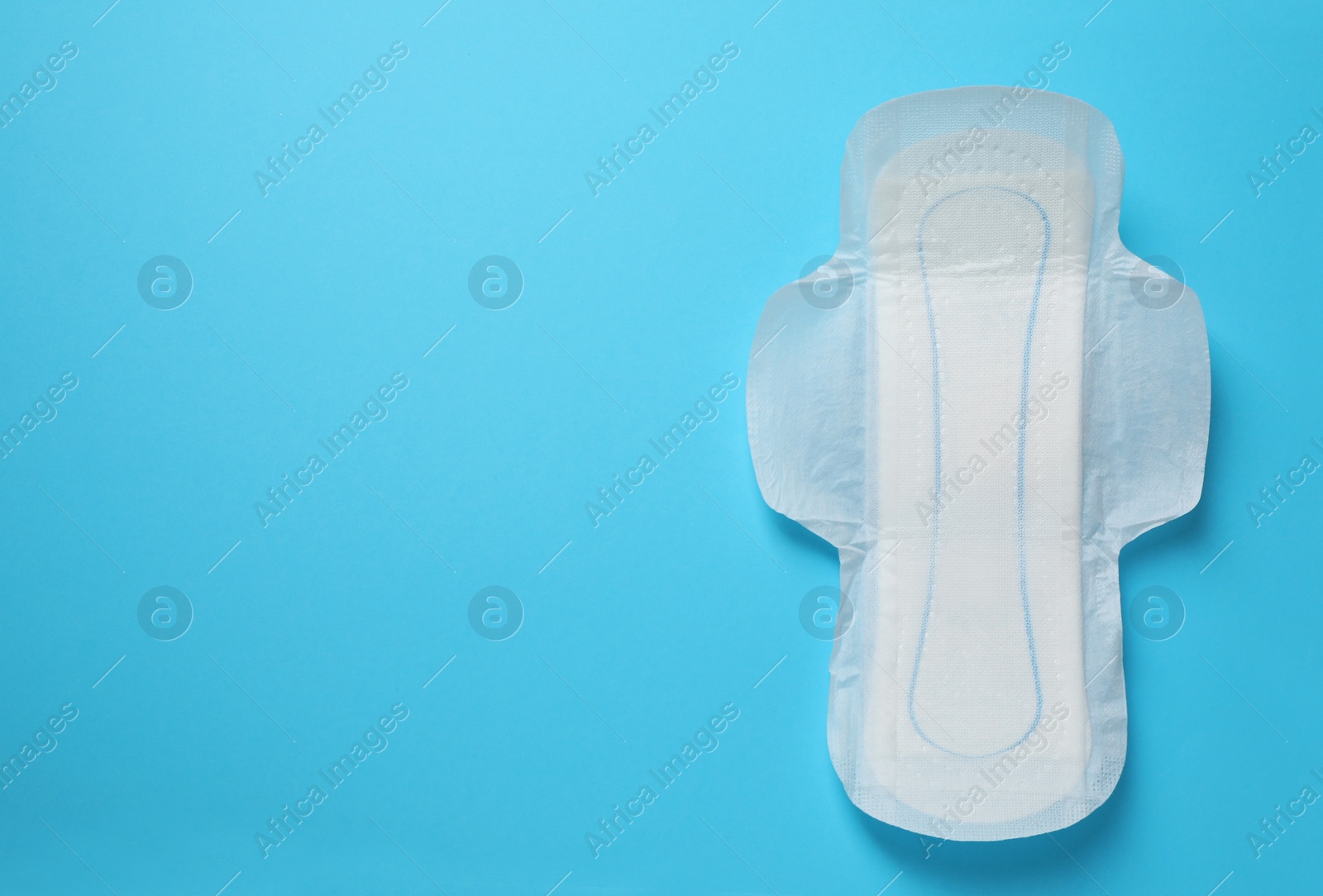 Photo of Sanitary napkin on light blue background, top view. Space for text