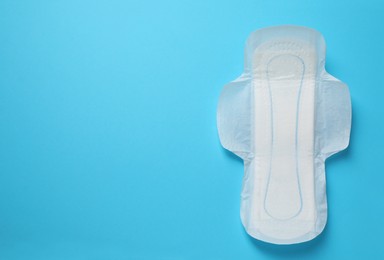 Photo of Sanitary napkin on light blue background, top view. Space for text