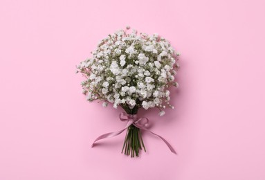 Bouquet of white gypsophila with ribbon on pink background, top view