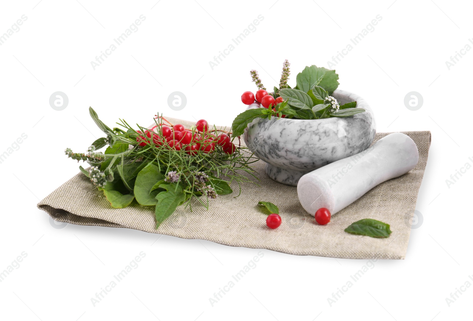 Photo of Cloth and marble mortar with different herbs, berries and pestle on white background