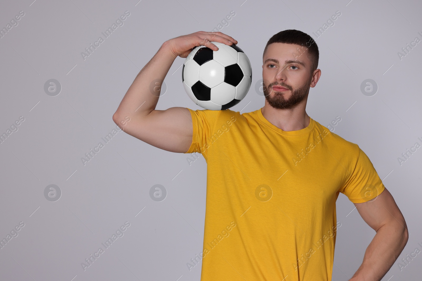 Photo of Athletic young man with soccer ball on light grey background