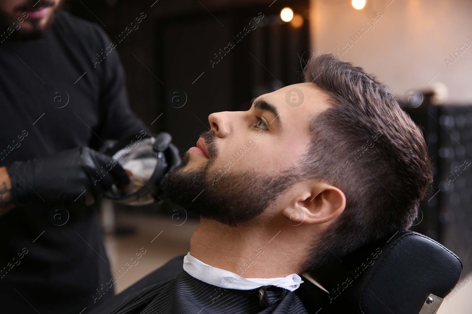 Photo of Young man visiting barbershop. Professional shaving service