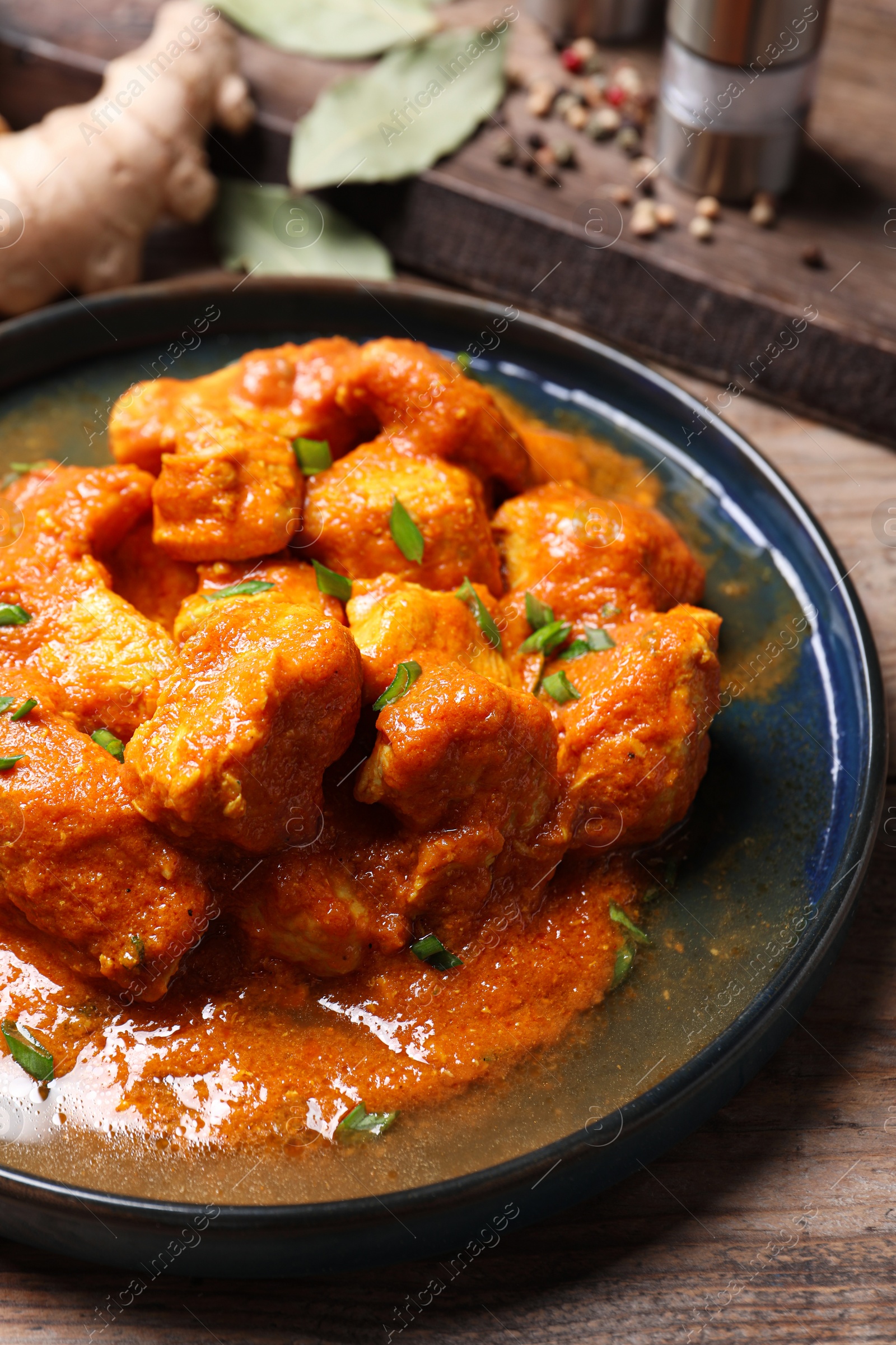 Photo of Plate of delicious chicken curry on wooden table, closeup