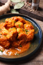 Plate of delicious chicken curry on wooden table, closeup