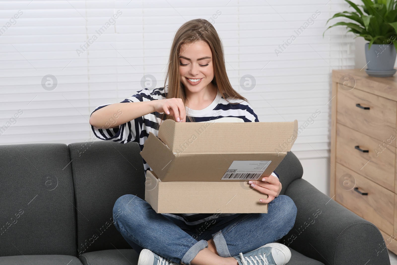 Photo of Happy woman unpacking parcel at home. Online store