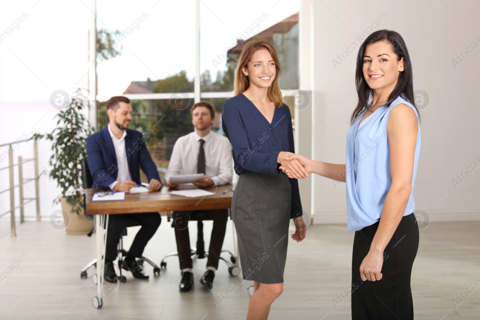 Photo of Human resources manager shaking hands with applicant during job interview in office