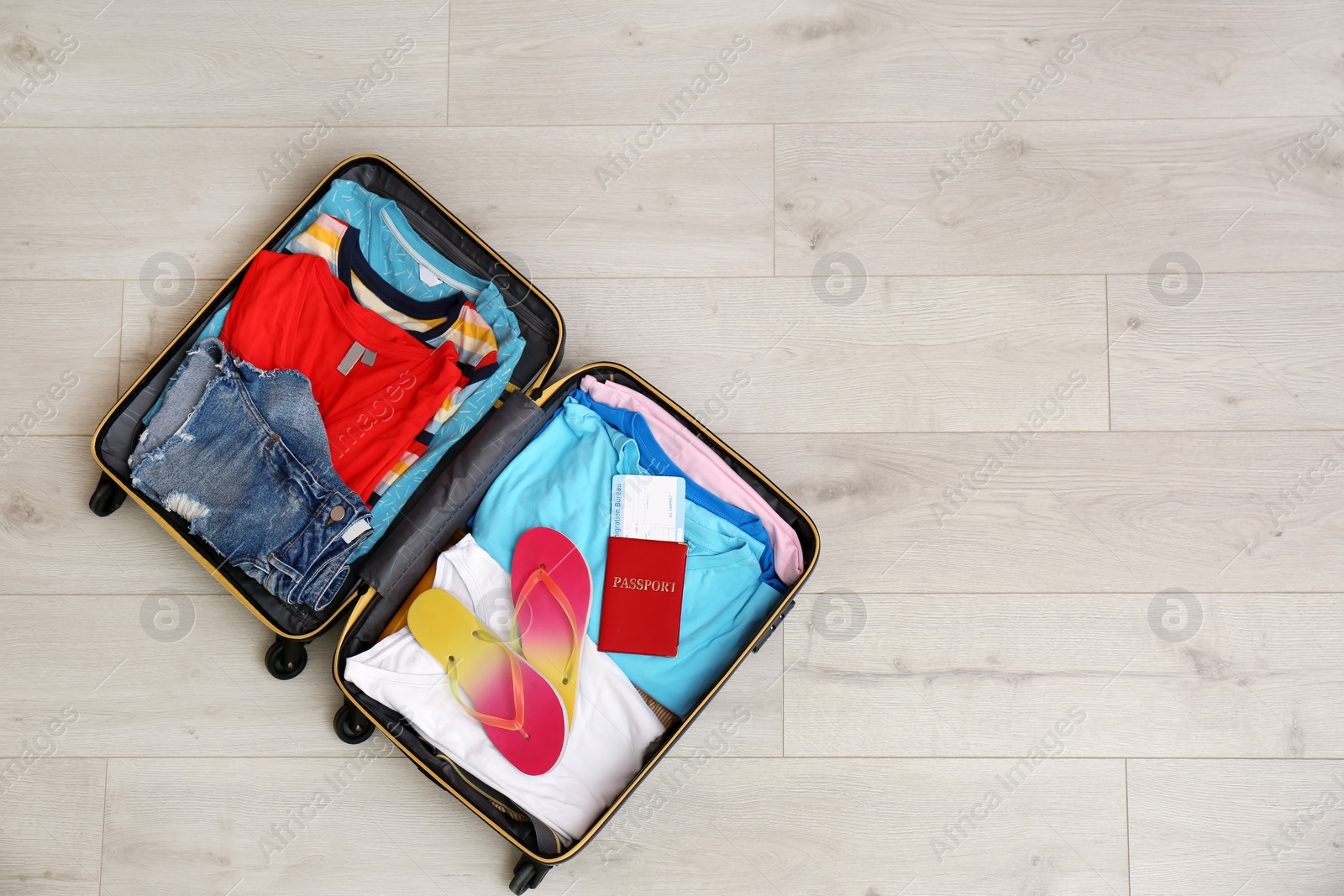 Photo of Packed suitcase with summer clothes and passport on wooden background, top view. Space for text