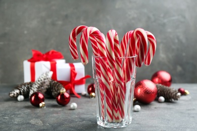 Photo of Many sweet candy canes in glass on grey table. Traditional Christmas treat