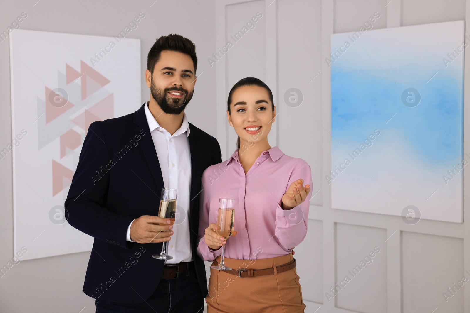 Photo of Young couple with glasses of champagne at exhibition in art gallery