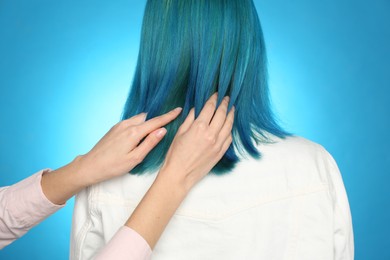Woman with bright dyed hair on light blue background, back view