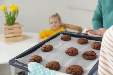 Photo of Woman with oven baked cookies and her family indoors, closeup