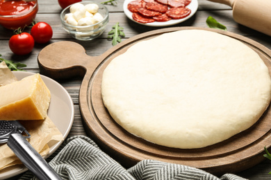 Photo of Dough and fresh ingredients for pepperoni pizza on wooden table