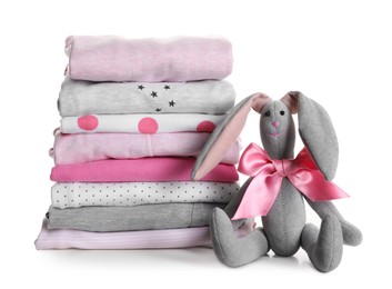 Photo of Stack of clean girl's clothes and toy bunny on white background