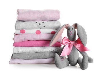 Stack of clean girl's clothes and toy bunny on white background