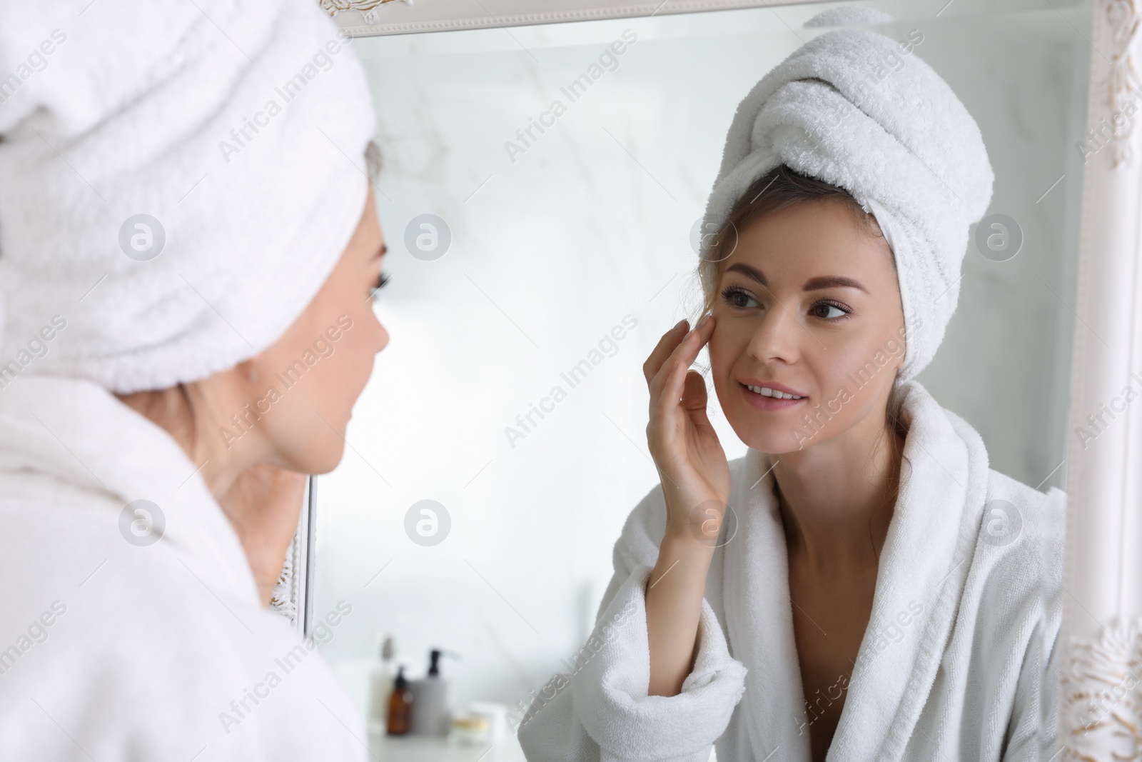 Photo of Beautiful woman looking at herself in bathroom mirror