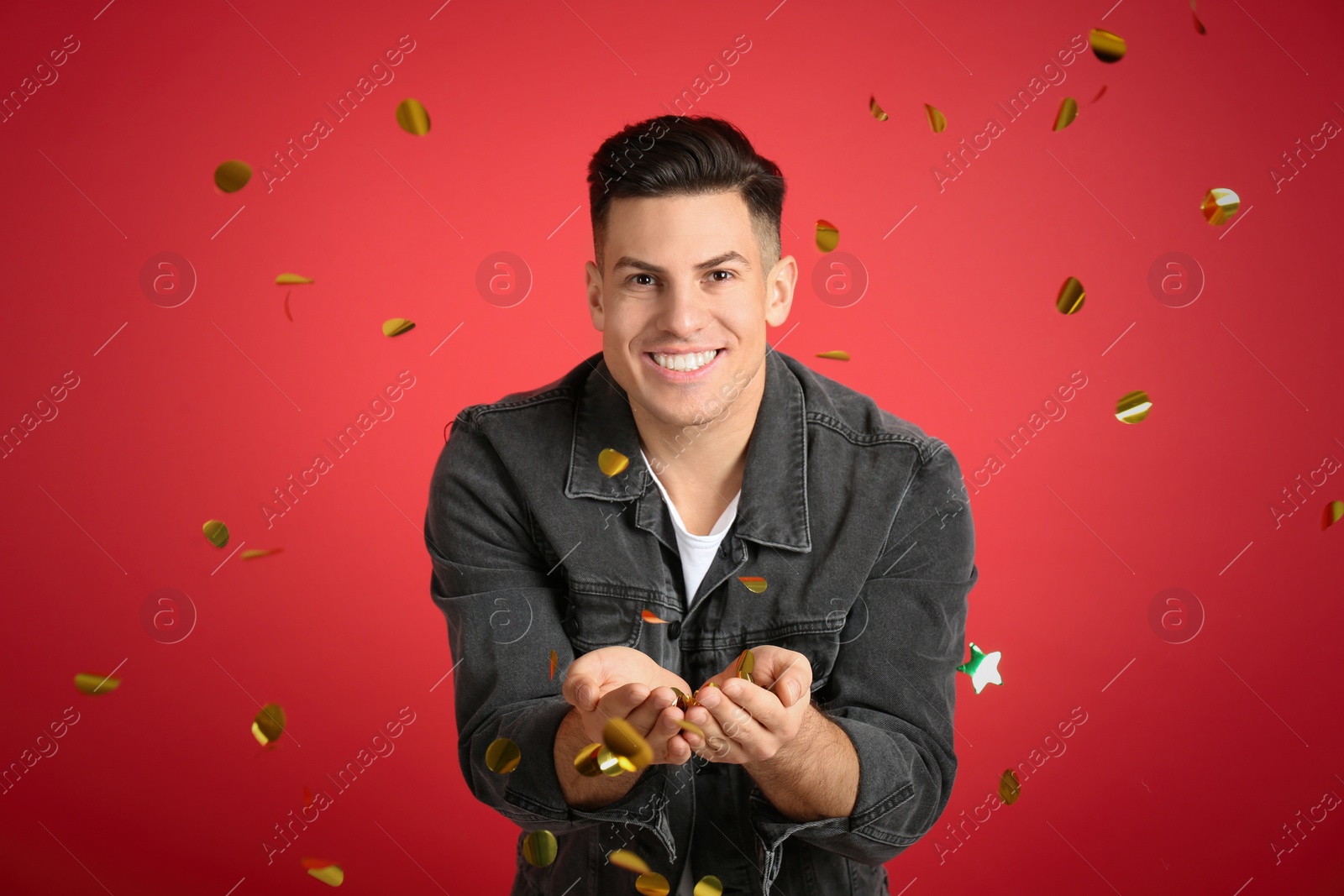 Photo of Happy man and falling confetti on red background