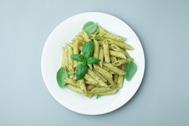 Photo of Delicious pasta with pesto sauce and basil on light grey background, top view