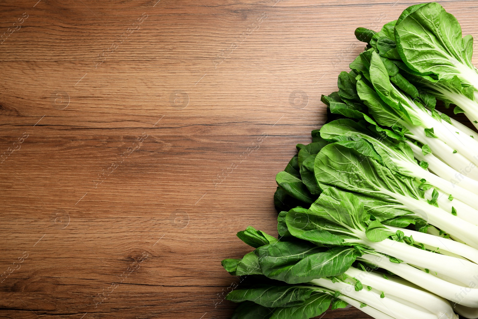 Photo of Fresh green pak choy cabbages on wooden table, flat lay. Space for text