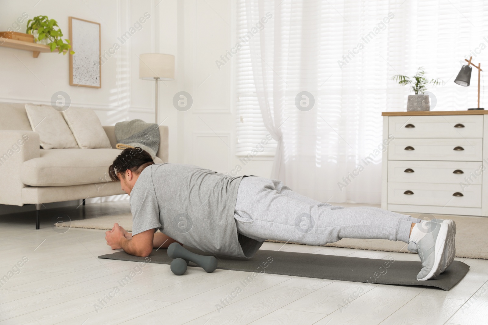 Photo of Overweight man doing plank exercise on mat at home