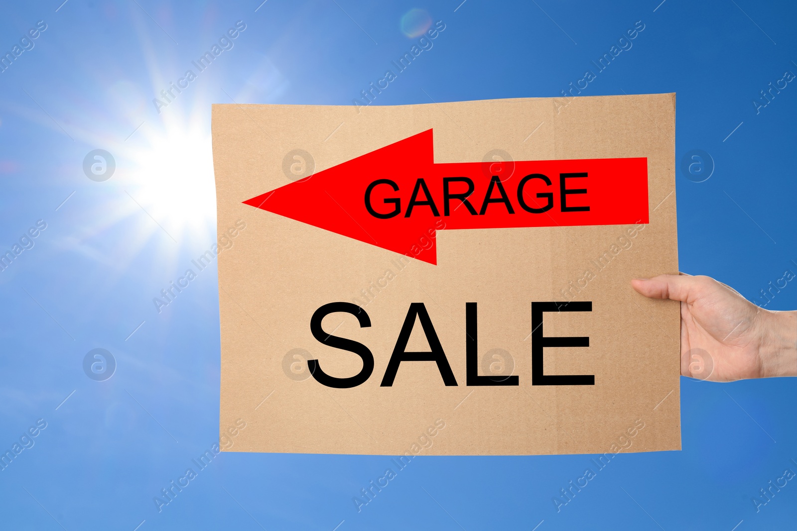 Image of Woman holding sign with text GARAGE SALE against blue sky