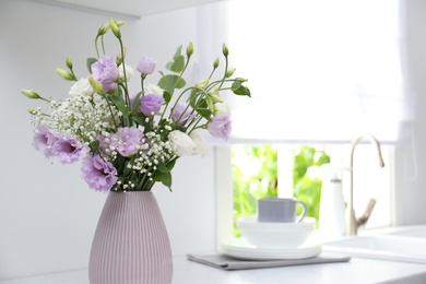 Beautiful bouquet with Eustoma flowers on countertop in kitchen, closeup. Space for text