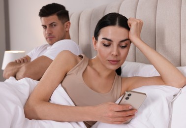 Internet addiction. Woman with smartphone ignoring her boyfriend in bedroom