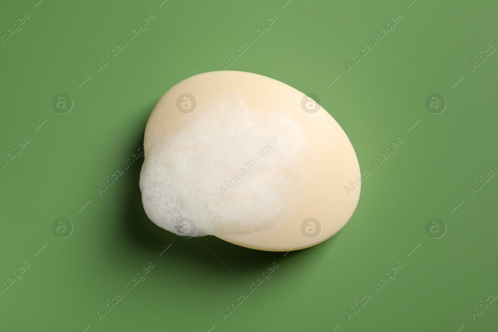 Photo of Soap and fluffy foam on green background, top view