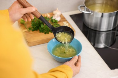 Photo of Man pouring delicious soup into bowl in kitchen, closeup