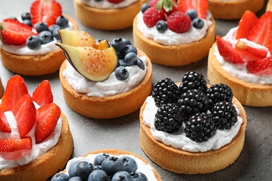 Photo of Many different berry tarts on table. Delicious pastries