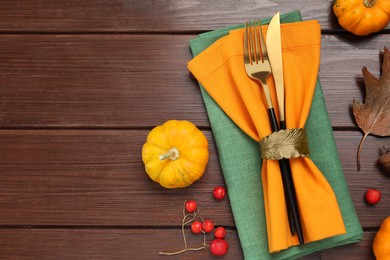 Photo of Cutlery, napkins and autumn decoration on wooden background, flat lay with space for text. Table setting