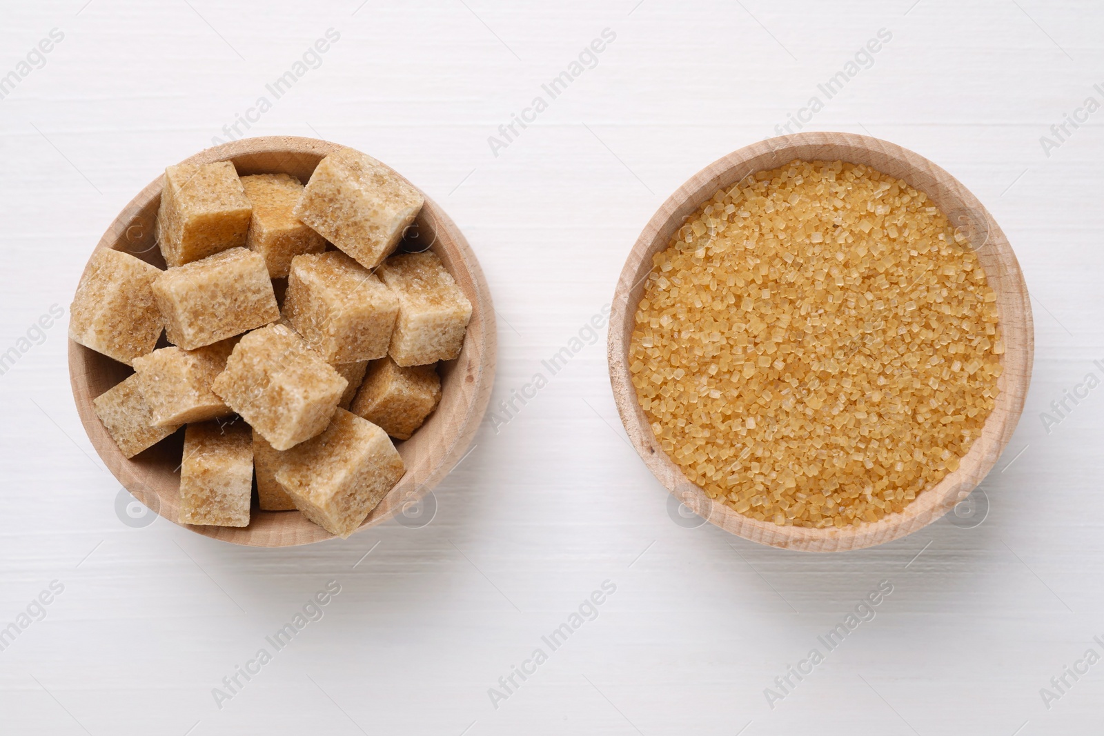 Photo of Different types of brown sugar in bowls on white table, flat lay